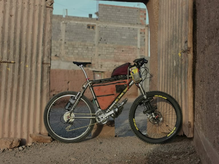 Michael Drummond's hardtail mountain bike with frame bag and saddle pack propped in a corrugated-iron gateway in Morocco.