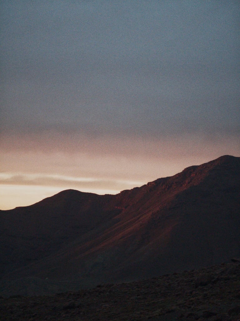 Dark mountain ridge under a pink and grey dusk sky as night falls on day one of the Atlas Mountain Race.