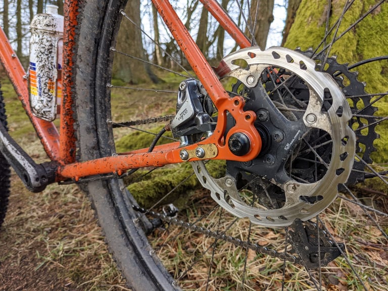 Mud-spattered Fairlight Secan rear dropout by Bentley Components with a SRAM Force caliper on a Shimano rotor.
