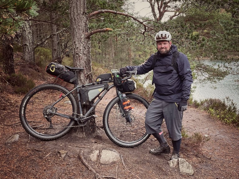 Al with his Mason ISO and its off-the-shelf Apidura frame bag beside a loch, before the bespoke StraightCut bag.