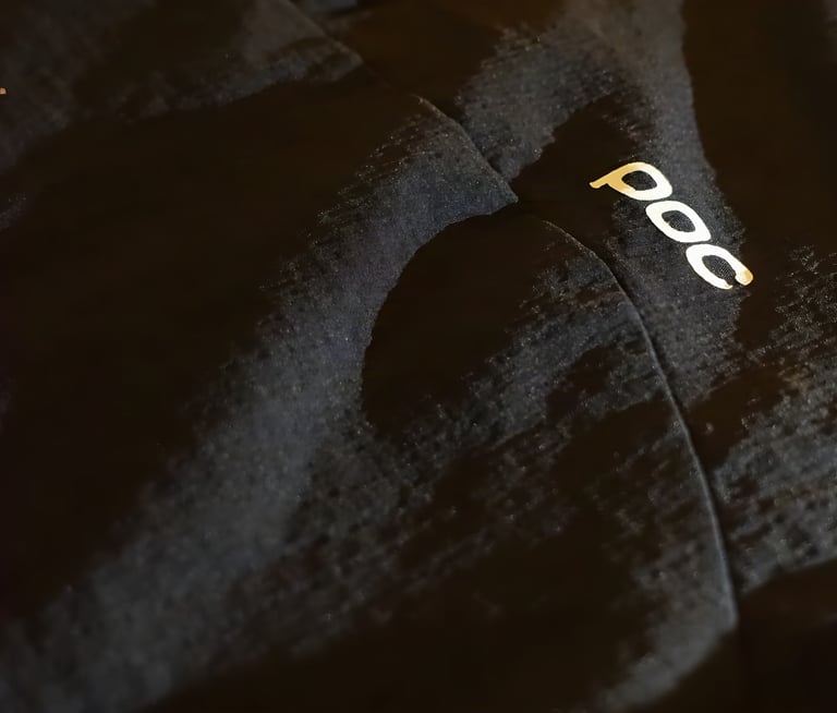 Close-up of the POC logo on the dark textured fabric of the Mantle thermal hoodie under review.