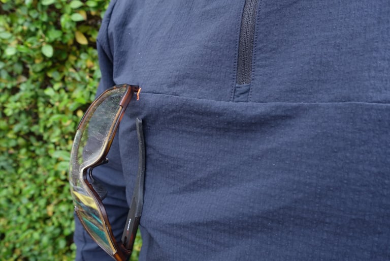 Glasses hang from the chest glasses holder of the POC Mantle hoodie, orange stitches marking the slot.